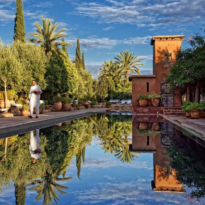 The reflecting pool at Kasbah Beldi, palms and a tower mirrored in the water