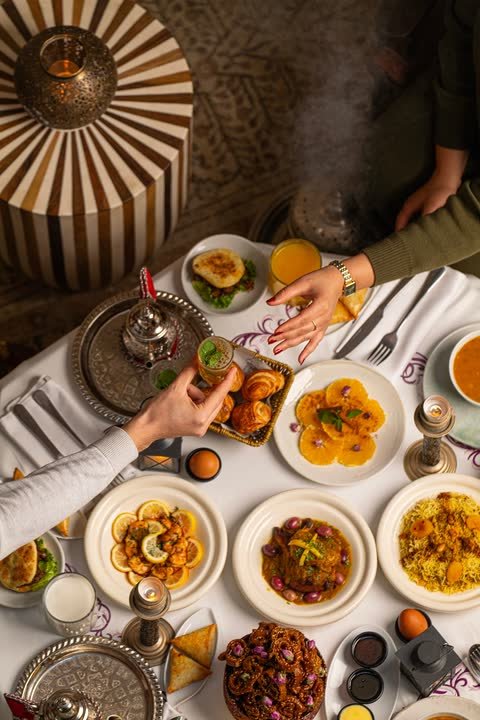 A shared Moroccan table of dishes and mint tea, seen from above