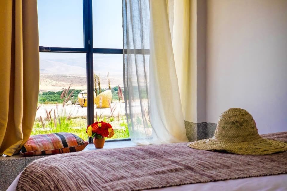 A guest room at Kasbah Beldi, a woven bed by a tall window